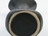 a black vase with a gold rim on a white background