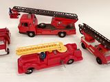 quatre camions de pompiers miniatures et un camion de pompiers posés sur une surface blanche