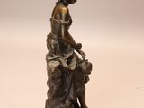 bronze statue of a woman sitting on a rock with a dog