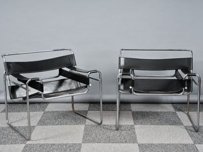 deux fauteuils en cuir noir placés l'un à côté de l'autre sur un sol à carreaux