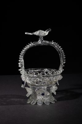 an old glass basket with a bird sitting on top of it