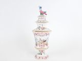 a white vase with a bird on top of it