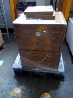 un homme debout à côté d'une pile de cartons posés sur un diable