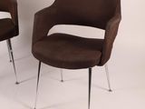 pair of brown chairs with chrome legs against a white wall
