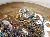 a wooden bowl filled with assorted jewelry on a table