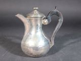 a silver coffee pot with a handle on a table
