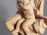 statue of a woman holding a baby and a child on a rock