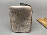 a small silver lighter sitting next to a lighter holder