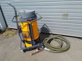a yellow machine with a hose next to a garage door