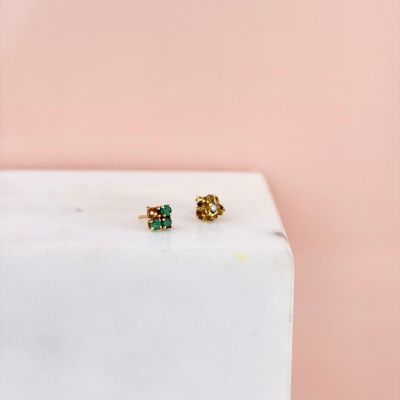 un gros plan sur une paire de boucles d'oreilles dorées et vertes posées sur un bloc de marbre