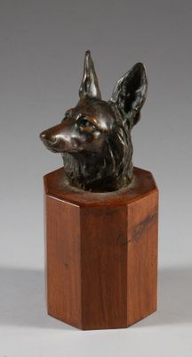 une image représentant une tête de chien en bronze posée sur un socle en bois