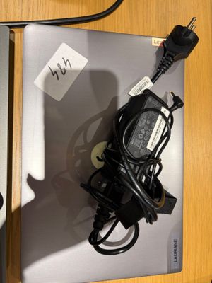 un ordinateur portable posé sur un bureau, avec un chargeur branché dessus
