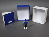 a small figurine of a man standing in front of a box