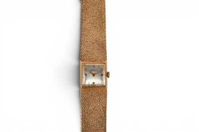 une image représentant une montre en or avec un cadran blanc et un bracelet marron