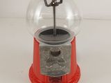 a red gum ball dispenser on a white surface