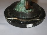 a bronze statue of a woman holding a bird on a pedestal