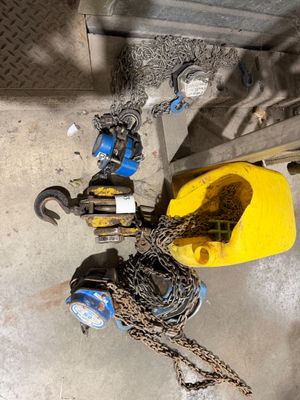 un seau jaune auquel sont attachées des chaînes, à côté d'une fourche jaune