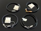 three black leather bracelets with white tags on them sitting on a table