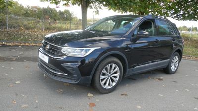 the black volkswagen suv is parked on the side of the road