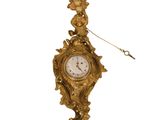 a gold clock hanging from the side of a wall