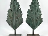 deux sculptures vertes représentant des feuilles, posées sur des socles, sur une surface blanche
