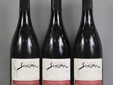 Trois bouteilles de vin sont alignées sur une table en verre