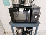 un micro-ondes et une cafetière posés sur une petite table bleue