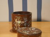 two small containers sitting on a table with blue and white striped wallpaper