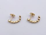 a pair of gold earrings on a white surface