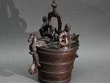 une statue en bronze représentant un homme et deux enfants dans un seau