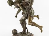an image of a bronze statue of a man and a woman playing with a soccer ball