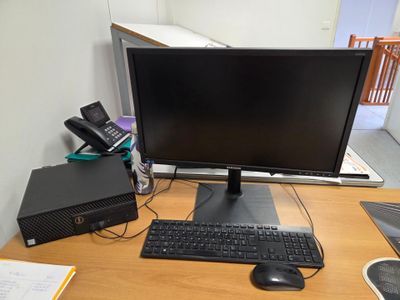 un écran d'ordinateur posé sur un bureau, à côté d'un clavier et d'une souris