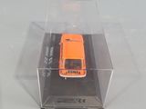 an orange toy truck in a clear box on a white surface