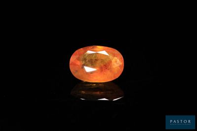 an orange sapphire stone on a black surface