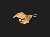 un gros plan sur une broche en feuille d'or ornée d'une perle