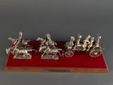 a silver figurine of a group of people riding in a horse drawn carriage