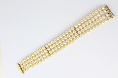 deux rangées de perles blanches avec des fermoirs dorés sur un fond blanc
