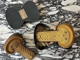 two pieces of gold and black hair clips sitting on top of a marble table