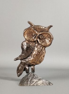 figurine de chouette en argent et en or, perchée sur un rocher, sur fond gris