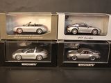 three boxed silver porsche models in boxes on a black surface