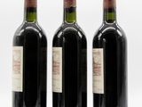 three bottles of wine are lined up on a white surface