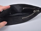 a person holding an empty black purse with a zipper