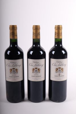 trois bouteilles de vin rouge sont alignées sur une surface blanche