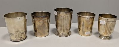 quatre tasses en argent sont alignées sur une surface blanche
