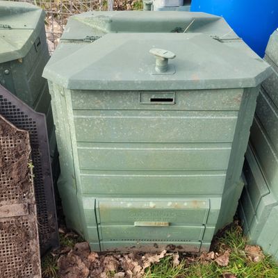 many green bins sitting next to each other in the grass