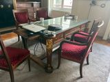 a glass table with red chairs and a laptop on it
