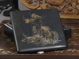 une boîte noire ornée d'une peinture, posée sur une table