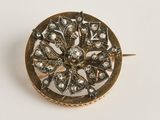 gros plan d'une broche en or sur une surface blanche