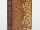 Un vieux livre orné d'un motif décoratif repose sur une surface blanche