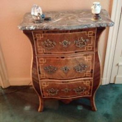 a marble top chest of drawers in the corner of a room